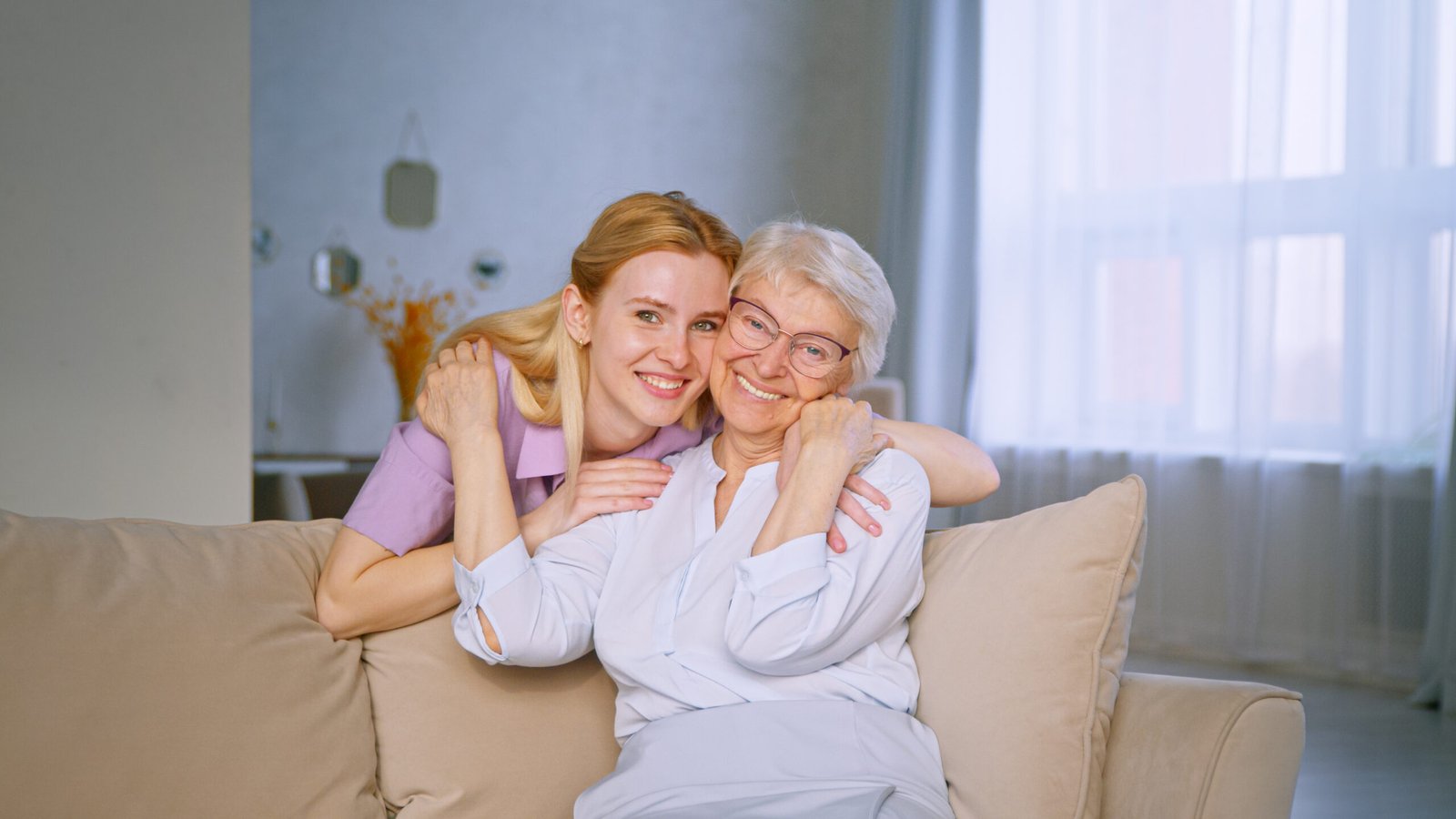 young-girl-and-elderly-woman-embracing-on-a-couch-2024-09-22-17-13-17-utc