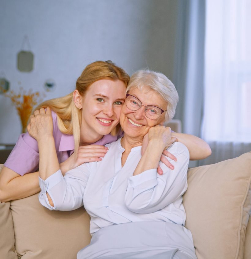 young-girl-and-elderly-woman-embracing-on-a-couch-2024-09-22-17-13-17-utc